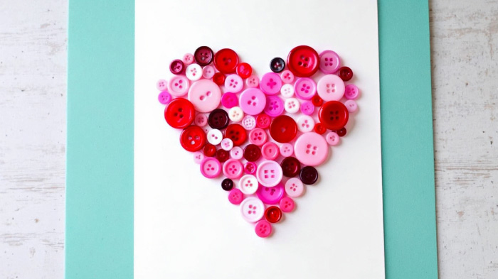 A collection of colorful buttons arranged in a heart shape, adding texture and charm to a Valentine’s Day card.