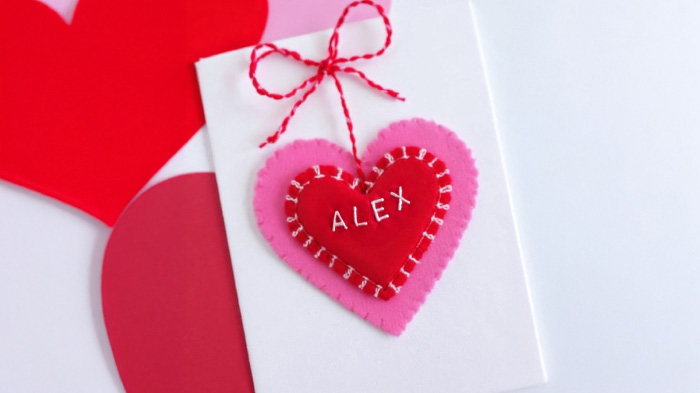 A fabric card featuring a stitched heart or initials, adding a personal and cozy embroidered detail.